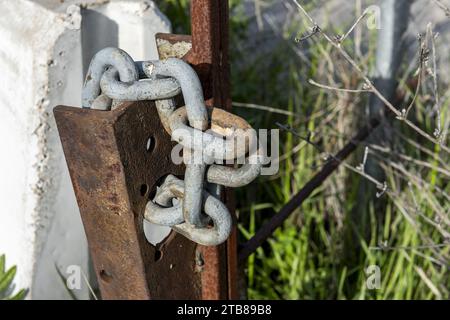 Catene in acciaio inox che avvolgono un palo in metallo arrugginito Foto Stock