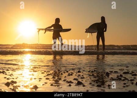 Vielle-Saint-Girons (Francia sud-occidentale): Giovani donne, surfisti, in piedi sulla spiaggia con le loro tavole da surf, di fronte all'Oceano Atlantico, guardando t Foto Stock