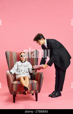 Studentessa sicura di sé vestita con abiti da donna e occhiali da sole seduti su una comoda sedia e alla cieca firma i documenti della segretaria Foto Stock