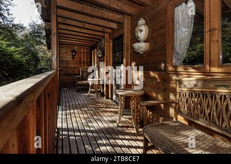 Portico anteriore di una cabina di legno con mobili in legno e vimini Foto Stock