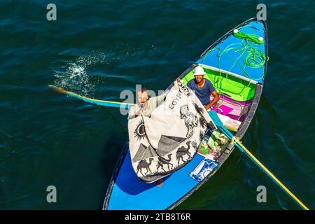 I venditori di tessuti sulle loro barche si avvicinano a una nave da crociera in attesa di entrare nella chiusa di Esna. I venditori sperano di vendere beni ai turisti. Esna, Egitto – 20 ottobre Foto Stock