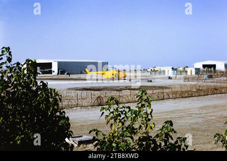 Scansione vetrino di archivio. Royal Air Force, Westland Whirlwind HAR.2 elicottero, XL111, del volo di ricerca e salvataggio RAF Khormaksar si prepara a decollare dalla RAF Khormaksar, Aden. 1966. Sullo sfondo un elicottero Belvedere è in un hangar, e i jet da combattimento Hawker Hunter sono allineati sulla padella. Foto Stock