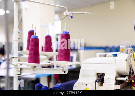 Primo piano della bobina viola delle filettature da cucire che si srotolano sulla macchina da cucire Foto Stock