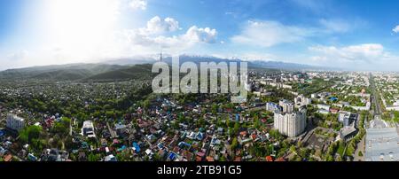 Vista panoramica aerea della città di Almaty con la Torre della televisione durante il soleggiato giorno primaverile con montagne innevate sullo sfondo Foto Stock