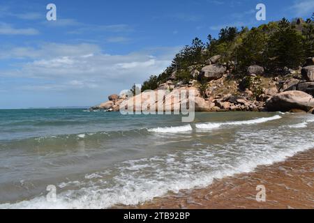 Scena della spiaggia ad Alma Bay con rocce di granito e Hoop Pines sullo sfondo, tipico della costa di Magnetic Island, Queensland, Australia Foto Stock