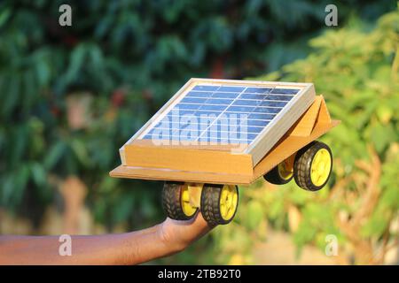 Auto solare o solare tenuta in mano. Il pannello solare converte l'energia del sole e aziona le ruote collegate al motore CC Foto Stock