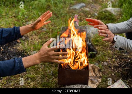 Primo piano di due uomini che scaldano le mani dal fuoco Foto Stock