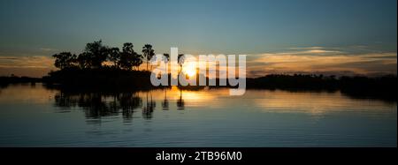 Sole che tramonta su un corpo d'acqua nella riserva di Selinda; riserva di Selinda, Botswana Foto Stock