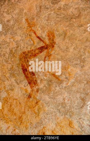 Figura umana che si piega e raggiunge raffigurata su un muro di roccia, parte della collezione di dipinti Bradshaw Rock di arte preistorica australiana Foto Stock