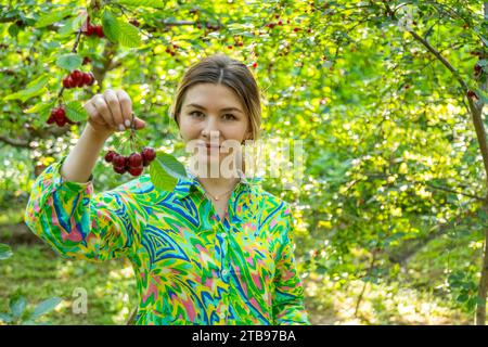 Donna in abito colorato con un mazzo di ciliegie in mano Foto Stock