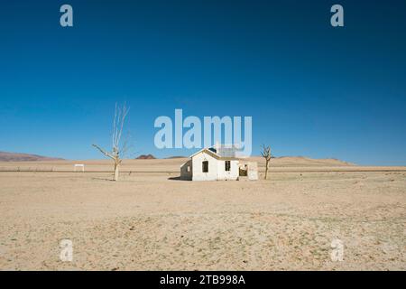 Casa abbandonata vicino a una linea ferroviaria che attraversa un deserto; Namibia Foto Stock