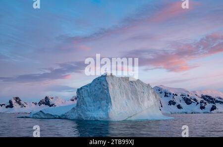 Iceberg e cielo al tramonto intorno a mezzanotte nell'estate antartica; Paradise Bay, Antartide Foto Stock