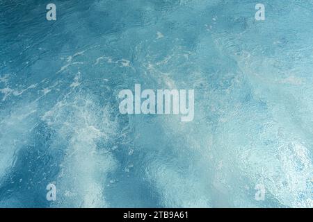 Acqua della piscina blu vorticosa con riflessi luminosi e dolci increspature in un hotel spa Foto Stock
