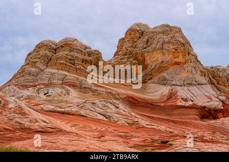 Donna seduta tra le enormi formazioni di roccia rossa sotto un cielo nuvoloso circondato dai tumuli erosi e dai fantastici motivi che formano la lan aliena... Foto Stock