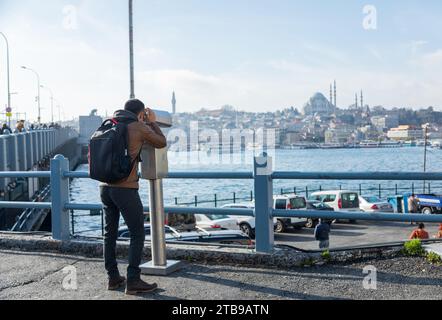 Giovane uomo che guarda attraverso il binocolo alla moschea blu di Istanbul Foto Stock