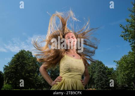 I capelli biondi della ragazza adolescente si alzano intorno alla testa mentre guarda in basso e sorride la telecamera; Lincoln, Nebraska, Stati Uniti d'America Foto Stock