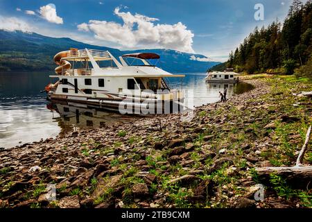 Una famiglia che si gode una vacanza in casa galleggiante mentre è parcheggiata sulla riva del lago Shuswap; lago Shuswap, British Columbia, Canada Foto Stock