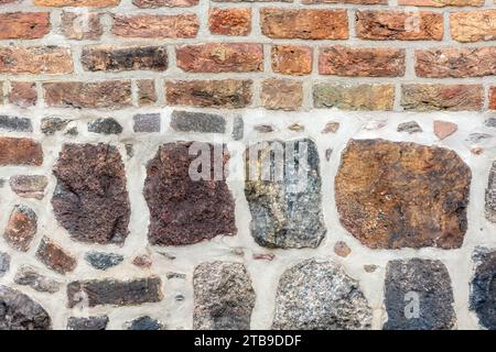 Frammento di un vecchio muro, fatto di pietre grezze di varie dimensioni e mattoni rossi. Per l'uso come sfondi e texture astratti. Foto Stock
