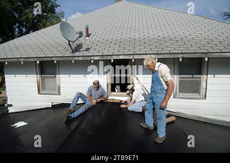 La famiglia sostituisce il tetto di una vecchia casa colonica; Schuyler, Nebraska, Stati Uniti d'America Foto Stock