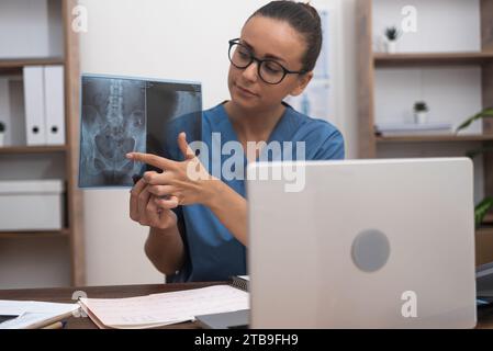 Medico che mostra pellicole radiografiche al paziente in portatile, fornendo al paziente una comprensione della malattia Foto Stock