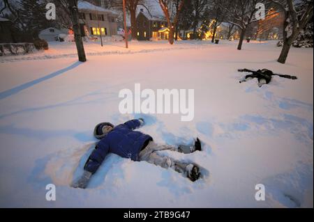 Due fratelli fanno angeli di neve nel loro cortile di fronte; Lincoln, Nebraska, Stati Uniti d'America Foto Stock