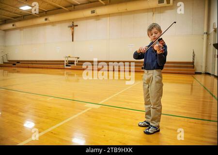 Il ragazzo pratica il suo violino in una palestra prima di un talent show; Lincoln, Nebraska, Stati Uniti d'America Foto Stock