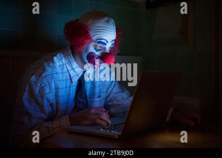 Clown che indossa una camicia e una cravatta usa un computer portatile per navigare in rete; Lincoln, Nebraska, Stati Uniti d'America Foto Stock