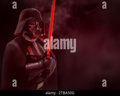NEC, BIRMINGHAM, REGNO UNITO - 3 DICEMBRE 2023. Un cosplay maschile in un evento comico nel costume di Dart Fener di Star Wars con una spada laser rossa in un dramma Foto Stock