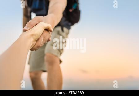 Escursionisti che scalano la montagna, dando una mano ad un amico. Foto Stock