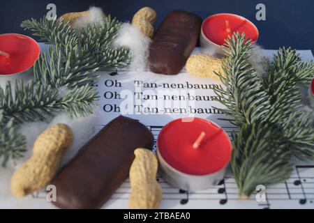 Spartito musicale con la canzone di Natale "Oh Tannenbaum", decorata con luci da tè, arachidi, stampe e ramoscelli di abete Foto Stock