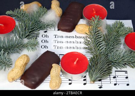 Spartito musicale con la canzone di Natale "Oh Tannenbaum", decorata con luci da tè, arachidi, stampe e ramoscelli di abete Foto Stock