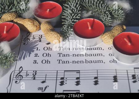 Spartito musicale con la canzone di Natale "Oh Tannenbaum", decorata con luci da tè, arachidi e ramoscelli di abete Foto Stock