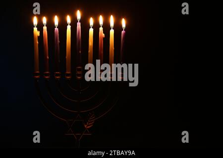 Festa di Hanukkah. Menorah con candele accese nel buio, spazio per il testo Foto Stock
