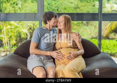 Un momento tenero catturato mentre un marito e una moglie incinta si siedono sul divano, condividendo un abbraccio affettuoso, il loro amore e la loro anticipazione si irradiano nel loro Foto Stock