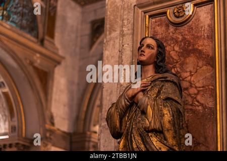 statua classica della vergine maria che prega con fede, con volto malinconico in una vecchia chiesa della cattedrale. Foto Stock