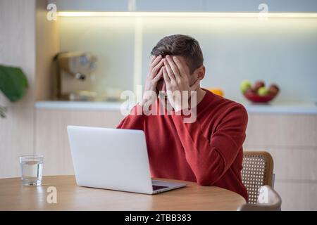 Distratto, frustrato e triste, l'uomo ha difficoltà finanziarie dopo essere stato licenziato dal lavoro chiudendo faccia a mano Foto Stock