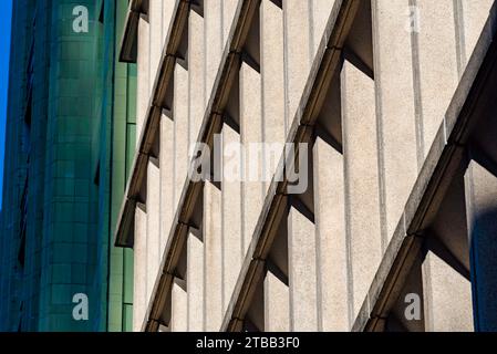 Un edificio anonimo e generico in cemento a Sydney, Australia, alla luce del sole del pomeriggio, che mostra linee verticali e diagonali contrastanti Foto Stock