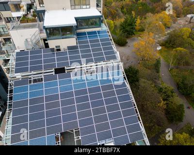 Volo con droni lungo la facciata di un moderno edificio residenziale o di uffici con pannelli solari sul tetto Foto Stock
