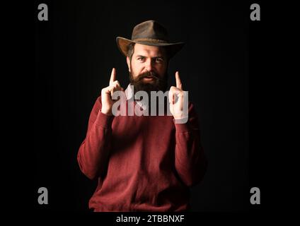 Divertente uomo cowboy in cappello cowboy. Fucili a ovest selvaggio, tiro a ruota con le dita. Cowboy man punta dita pistola Foto Stock