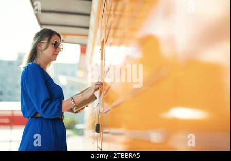 Donna che invia posta tramite terminale automatico self-service. Foto Stock