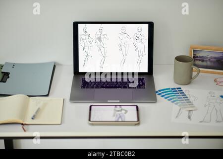 Notebook con schizzi di moda sullo schermo sulla scrivania del designer Foto Stock