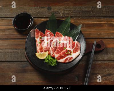 Affettato di maiale crudo e striato in un piatto bianco per lo Yakiniku, il Sukiyaki, il barbecue e lo Shabu. Foto Stock