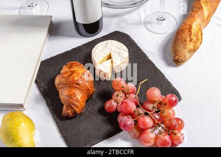 Dolci e formaggio su un tavolo, con frutta, bottiglia di vino rosso e bicchieri. Foto Stock