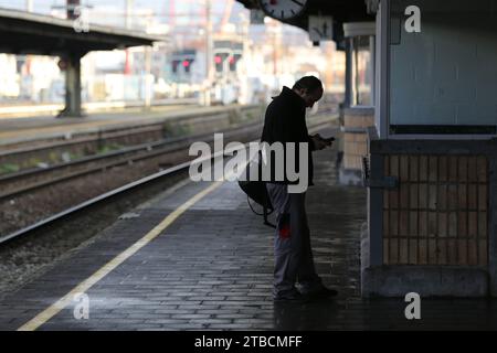 Bruxelles, Belgio. 6 dicembre 2023. Un passeggero utilizza un telefono cellulare sul binario di una stazione ferroviaria di Bruxelles, Belgio, 6 dicembre 2023. Il viaggio delle persone è influenzato in alcune parti del Belgio a causa di uno sciopero di 48 ore da parte dei membri del personale del sistema ferroviario. Crediti: Zhao Dingzhe/Xinhua/Alamy Live News Foto Stock