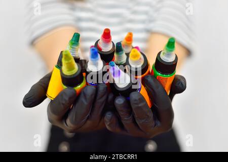 Donna maestra dell'arte del tatuaggio che tiene bottiglie di inchiostro colorato per tatuaggio. Concetto di arte e design. Primo piano Foto Stock