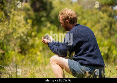 scienziato del suolo agronomo agricoltore che guarda campioni di suolo e erba in un campo in primavera. guardando la crescita delle piante e la salute del suolo in primavera Foto Stock