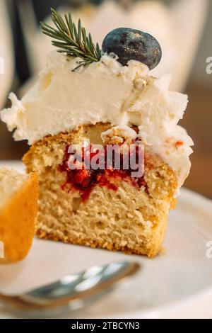 Metà cupcake con ripieno di frutta decorati con frutti di bosco con un ramo dell'albero di Natale su un piatto bianco Foto Stock