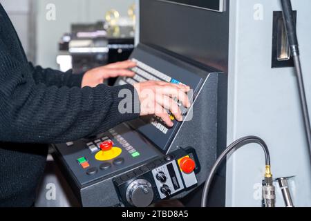 Primo piano delle mani di un lavoratore manuale industriale che utilizza il pannello di controllo nell'industria cnc Foto Stock