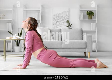 Giovane donna con dreadlock che fa yoga a casa Foto Stock