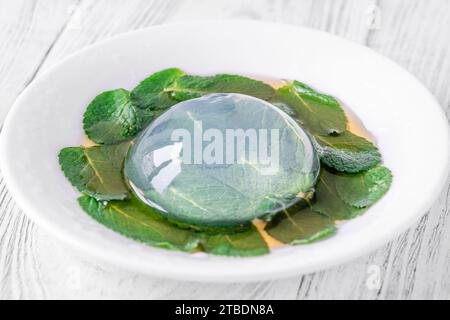 Porzione di torta con gocce di pioggia su foglie di menta Foto Stock